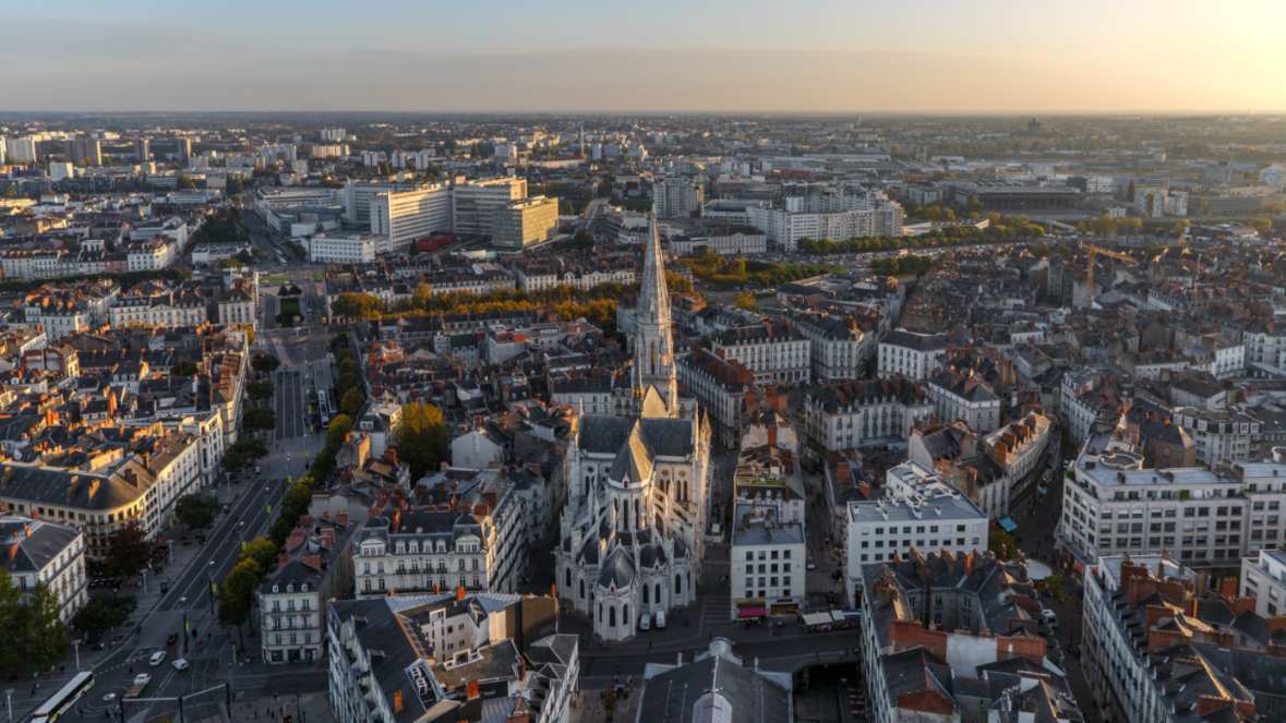 Vue aérienne urbaine plongeante sur le centre historique de Nantes avec la basilique Saint-Nicolas au coucher du soleil