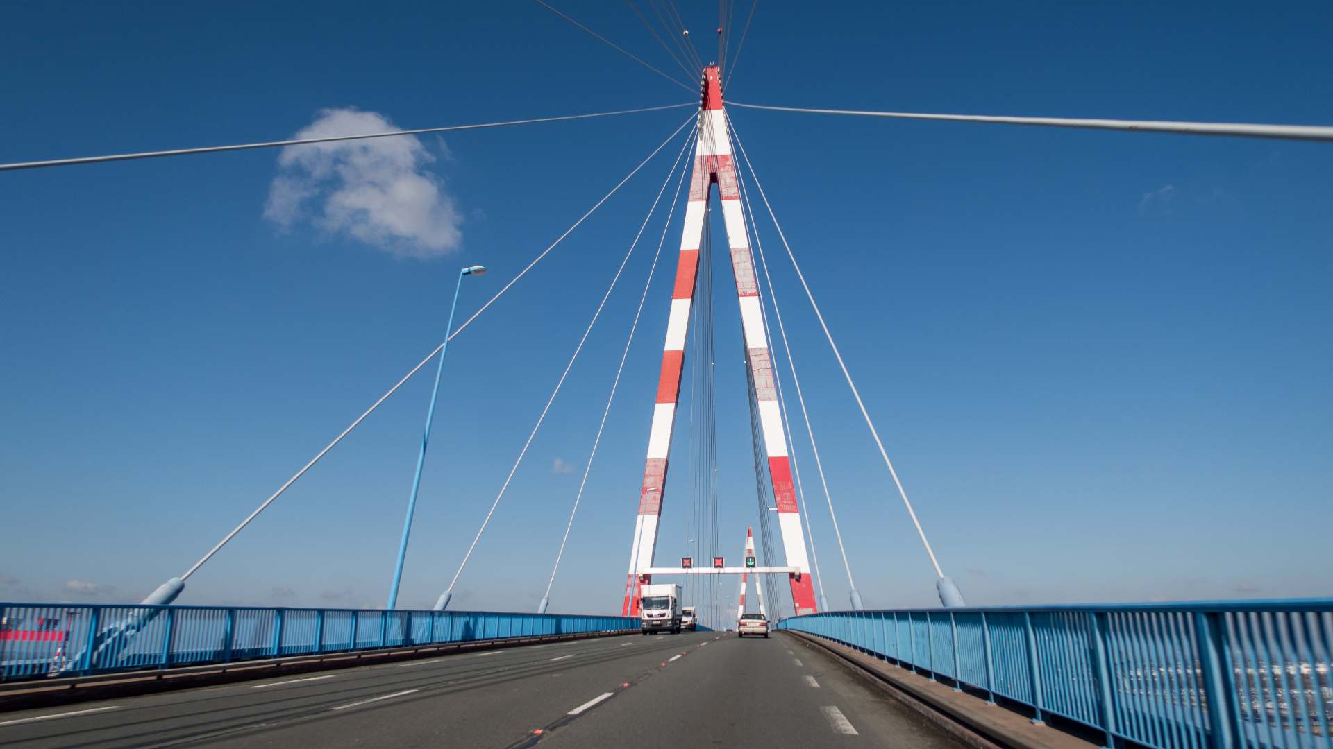 Vue frontale du tablier et du pylône rouge et blanc du pont de saint nazaire depuis la route sous un ciel bleu