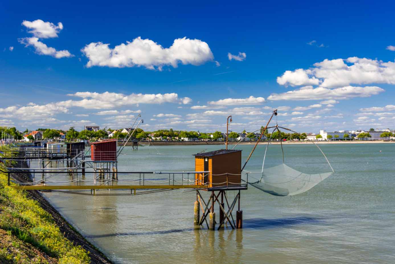 Carrelets de pêche sur pilotis en bois au-dessus de l'eau avec vue sur la côte sous un ciel bleu