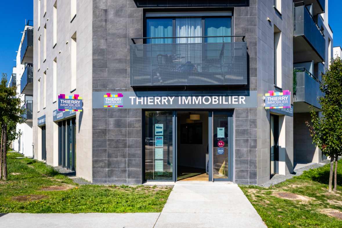 Façade moderne de l'agence immobilière Thierry Immobilier située en rez-de-chaussée d'un immeuble contemporain à Rezé