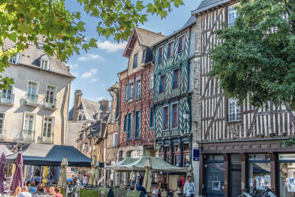Rue piétonne avec maisons à colombages médiévales et terrasses de café à Rennes