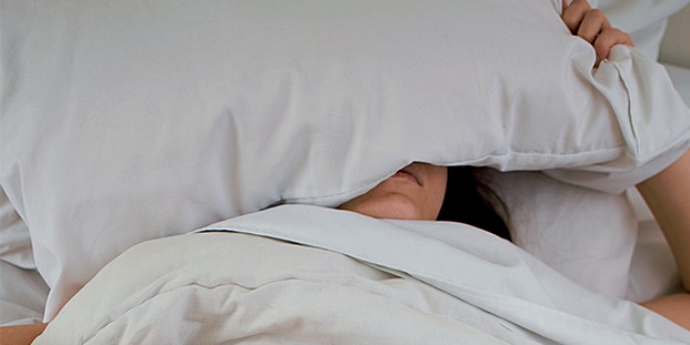 personne se cachant sous un oreiller dans une chambre confortable location nantes habitant original