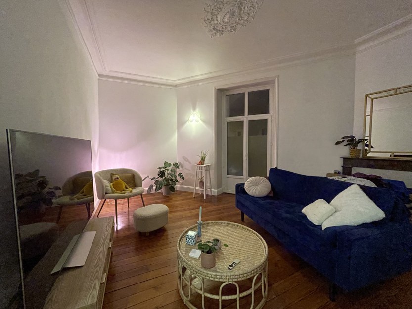 Salon d'appartement avec parquet en bois, moulures au plafond et canapé bleu