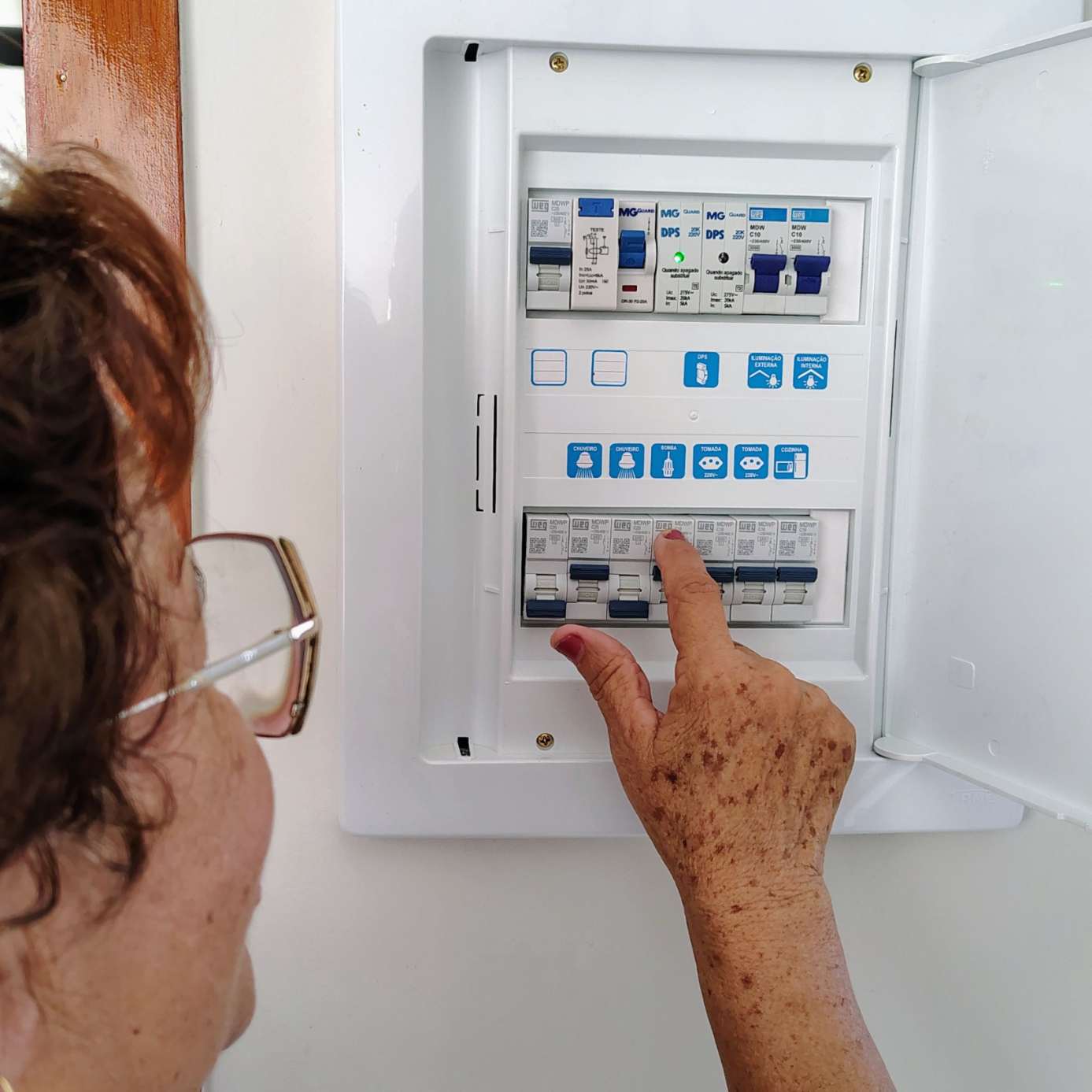 Une main active un disjoncteur sur un tableau électrique moderne et étiqueté