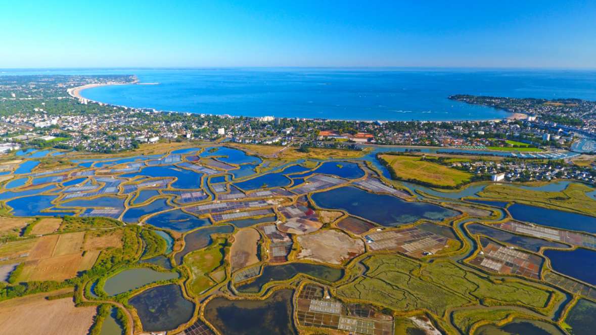 Vue aérienne des marais salants de Guérande avec la baie de La Baule en arrière-plan sous un ciel bleu